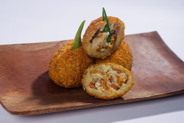 Delicious Indonesian snack named Risol or Risoles filled with smoked beef mayonnaise and crispy fried bread crumb texture on a wooden plate, isolated on a white background