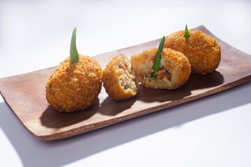 Delicious Indonesian snack named Risol or Risoles filled with smoked beef mayonnaise and crispy fried bread crumb texture on a wooden plate, isolated on a white background