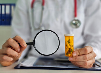 Doctor examining prescription medication with magnifying glass in medical office during regular consultation hours concept