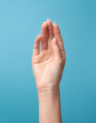 Close up Female hand holding something isolated on light blue