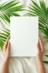 Minimalist tropics: hands holding blank paper with lush green palm leaves background