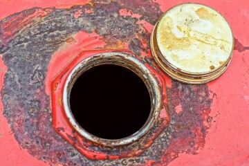 top of dirty round industrial old iron red with machine oil large open barrel with hole and gray lid