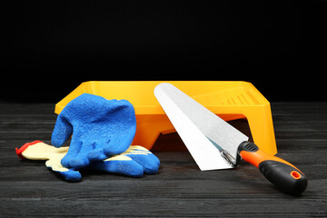 Tray, putty knife and rubber gloves on dark wooden table