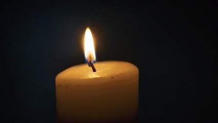 Eine brennende Kerze vor dunklem Hintergrund