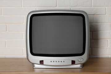 Retro tv set on wooden shelf against white brick wall