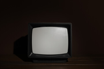 Retro tv set on wooden shelf against dark background