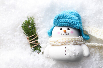 Cute decorative snowman and fir tree branches on artificial snow, flat lay