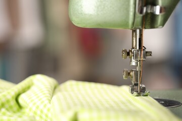 Vintage sewing machine with thread and fabric on blurred background, macro view. Space for text