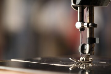 Sewing machine with thread on blurred background, macro view. Space for text