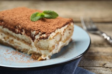 Piece of tasty tiramisu on wooden table, closeup