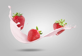 Strawberries and splashing milk or yogurt in air on light grey background