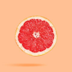 Sliced fresh juicy grapefruit in air on peach color background. Citrus fruit