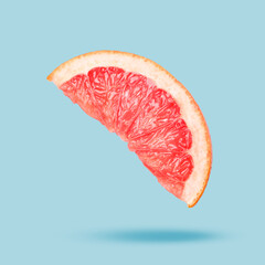Sliced fresh juicy grapefruit in air on light blue background. Citrus fruit