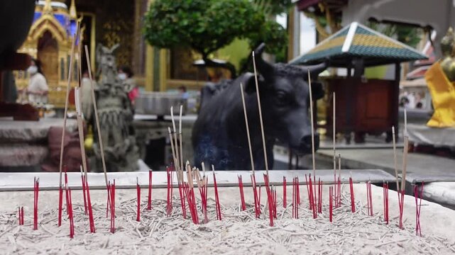 Serene Buddhist temple scene with lit incense sticks releasing smoke, creating a tranquil vibe. A detailed cow sculpture in the background adds cultural and spiritual depth, perfect for mindfulness th