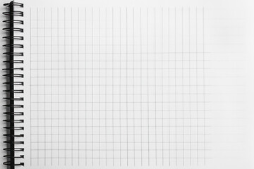 Blank paper on notebook, pen resting beside top corner, casting soft shadow on wooden desk surface.