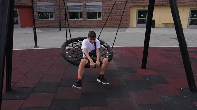 Kid with mental disability disease doing specific stimming tics patterns. Nervous autist boy teenager on the school playground.