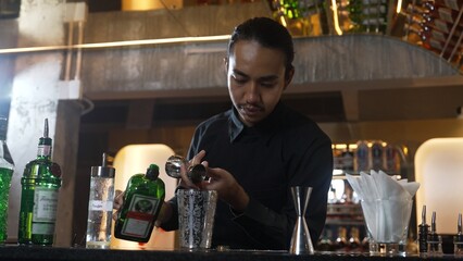 Asian bartender pouring mixed cocktail juice liqueur all ingredient into sliver shaker alcohol drink, making special advertisement creative tasty, focused refreshing showcase at bar luxury. Vinosity.