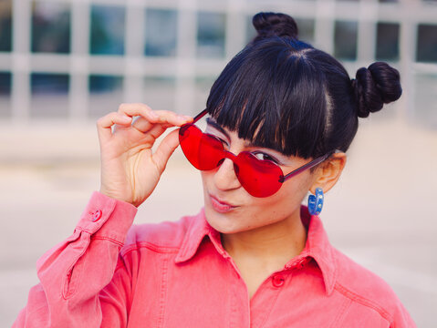 Brunette Latin young woman wink eye whit love and heart glasses while send a kiss whit mouth. Valentine's day 14 february concept. Pink clothes