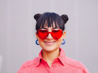 Love sunglasses latin america woman Close up portrait smiling, pink clothes. Red shape heart eyeglasses, brunette buns hair. Valentine day 14 february concept. Happy expression. Ecuador beauty