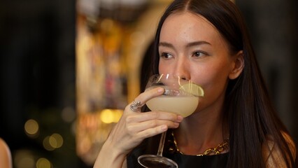 Smiling beautiful woman zipping Margarita cocktail savoring tasty drink making special time by bartender at luxurious bar creating moment meeting with friends or a couple vibrant nightclub. Vinosity.