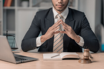 Lawyer working or reading law book working with laptop in office as legal counsel, justice and law. Male judge in courtroom on wooden table.