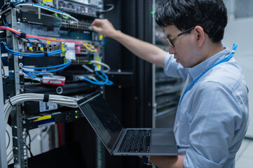 Computer engineer is setting up network in server room,Systems Maintenance Technician,Male engineer working in server room at modern data center
