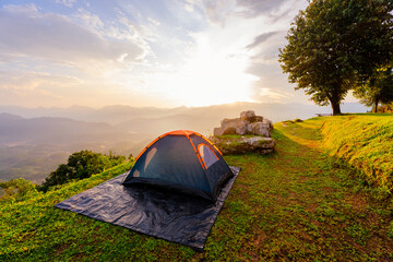 Adventurer tents at camping site with beautiful scenic sunset view point over layer of mountain for outdoor adventure vacation travel.