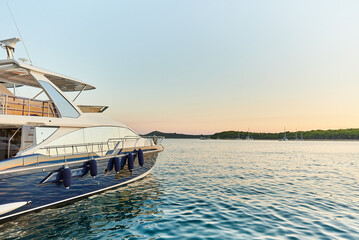 A luxury yacht moored in calm waters in the warm rays of the setting sun