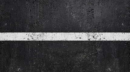 A close-up view of a textured asphalt surface with a prominent white line, commonly seen on roads for lane marking.