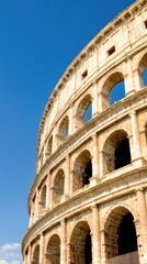 Fototapeta premium The majestic Colosseum rises against the vibrant blue sky, capturing the essence of ancient Rome with an artistic low-angle perspective