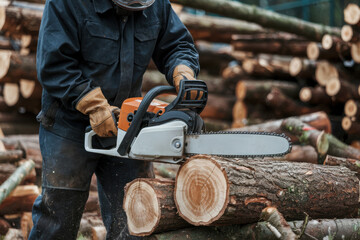 Lumberjack skillfully using a chainsaw to cut large logs in a professional timber harvesting operation in the forest.