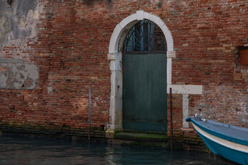 Ancient arched warehouse entrance and doors in Venice, giving direct access to the canal and boats.