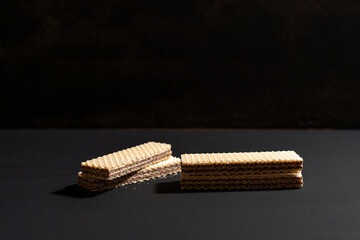 A close up of a few wafers on a black background. The wafers are stacked on top of each other and appear to be broken in half. Scene is simple and minimalistic