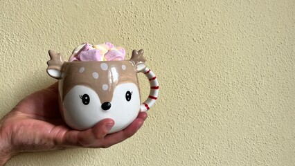 Christmas cup of cocoa and marshmallows held in hand.