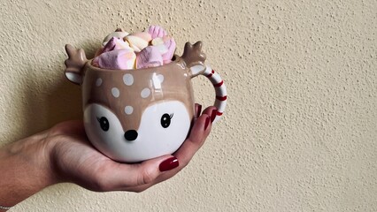 cute Christmas cup with cocoa and marshmallows in hand