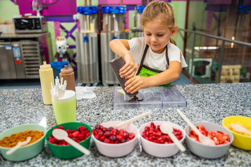 Little girl learning how to cook in a cooking class. Handmade dessert. Making chocolate candy, Child filling heart shaped mold with chocolate