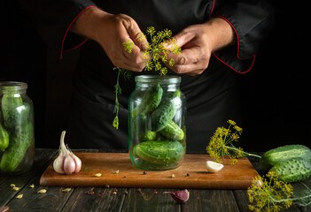 Hands skillfully add herbs to a jar filled with cucumbers, garlic, and spices. The warm ambiance of...
