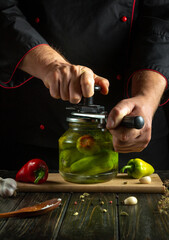 A skilled chef crafts homemade pickles, carefully pressing a lid onto a jar filled with vibrant peppers. The rustic kitchen ambiance enhances the artistic food preparation experience