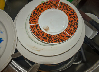 Dirty kitchenware, plates and mugs. Pile of unwashed, dirty dishes in the sink. Mess in the...
