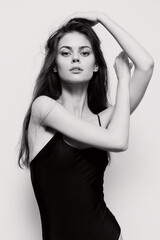 Fototapeta premium Elegant woman posing gracefully in a black swimsuit, showcasing beauty and confidence against a soft gray background. Fashion and body positivity concept.