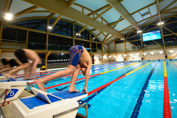 Boy swimmers start from the starting table in the pool