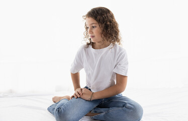 Fototapeta premium Thoughtful 7-year-old girl in casual studio portrait with natural light