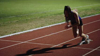 Female Runner on Athletics sprint race starting blocks on a dark background