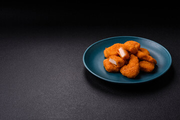 Delicious fresh crispy chicken nuggets on a dark concrete background