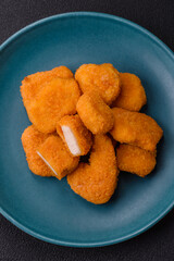 Delicious fresh crispy chicken nuggets on a dark concrete background