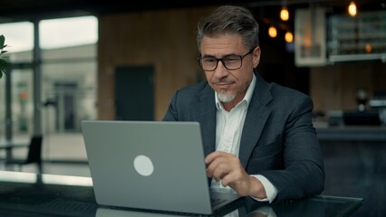 Confident male professional in jacket using laptop. Businessman remote working, managing business...