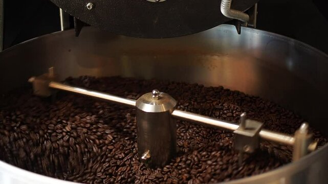 Coffee bean is poured out of the drum of the coffee roasting machine. Process of roasting coffee in production