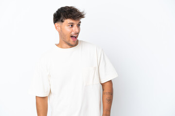 Obraz premium Young caucasian handsome man isolated on white background doing surprise gesture while looking to the side