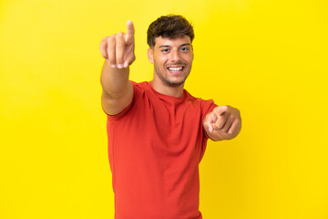 Young caucasian handsome man isolated on yellow background pointing front with happy expression