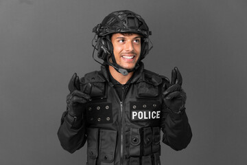 SWAT caucasian man isolated on grey background with fingers crossing